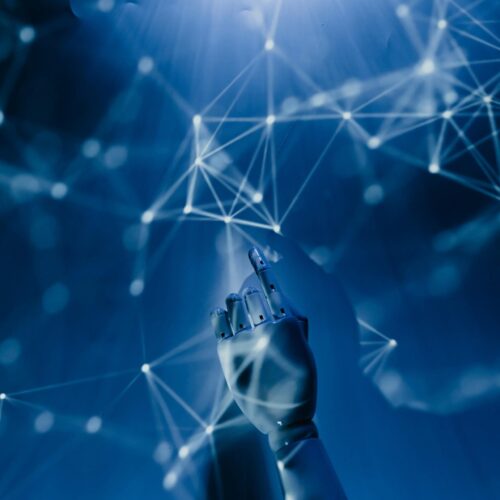 A robotic hand reaching into a digital network on a blue background, symbolizing AI technology.
